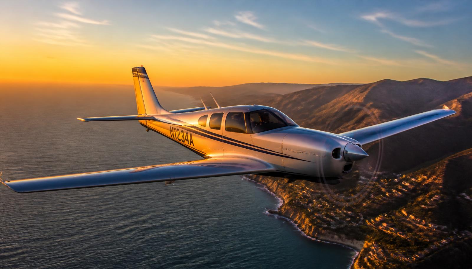 Avion léger privé survolant la côte au coucher du soleil